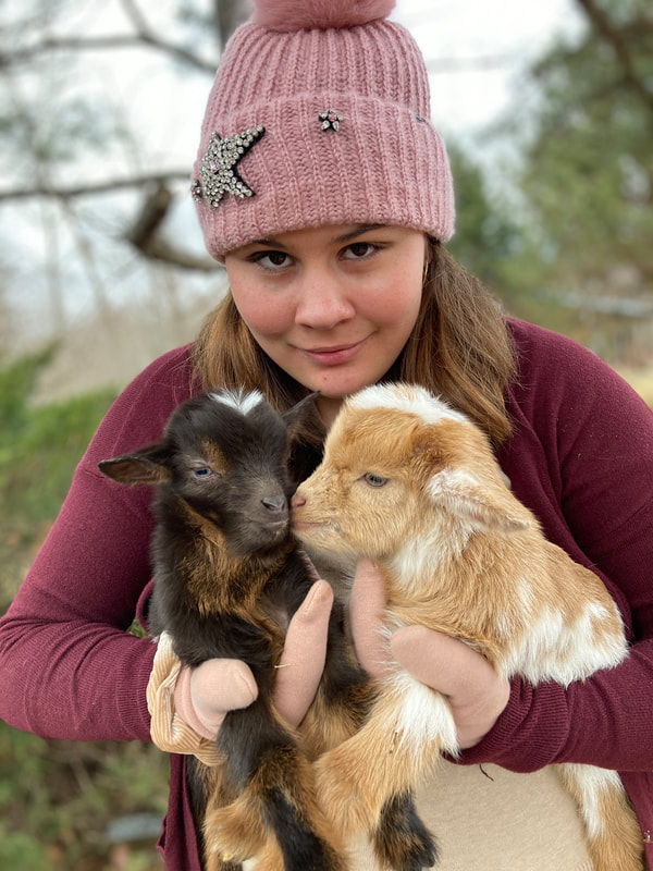 Claire Lea holding two baby goats at Dockley Ranch